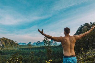 Rear view of shirtless man standing against sky