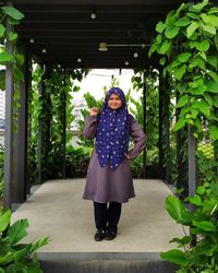 Portrait of woman standing against plants