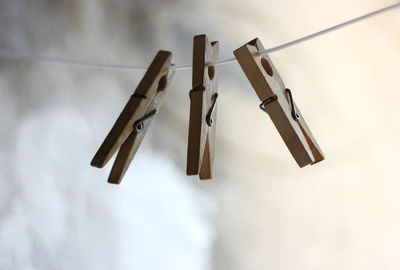 Low angle view of clothespins hanging on rope against sky