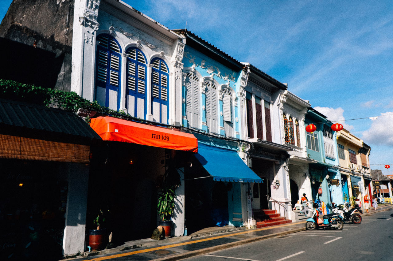 LOW ANGLE VIEW OF BUILDINGS BY ROAD AGAINST SKY