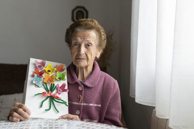 Senior woman showing craft sitting at dining table