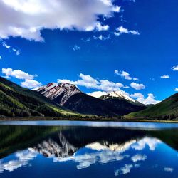 Reflection of mountains in lake against cloudy blue sky