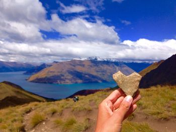 Close-up of hand holding hands against mountain range