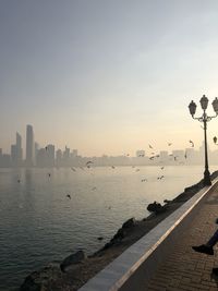 Scenic view of sea by buildings against sky during sunset