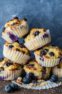 A pile of homemade blueberry muffins against a blue background.