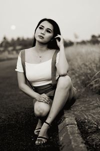 Portrait of a young woman sitting on field