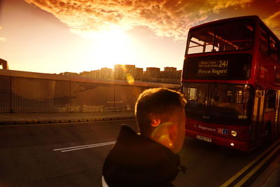Man in bus against sky during sunset