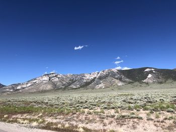 Scenic view of field and mountains against clear blue sky