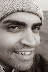 Close-up portrait of smiling young man wearing knit hat