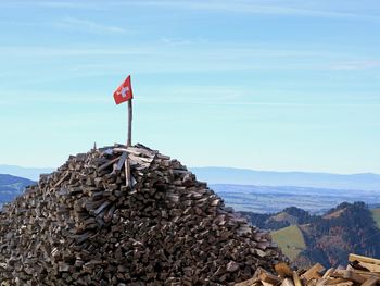 Flag on rock by sea against sky