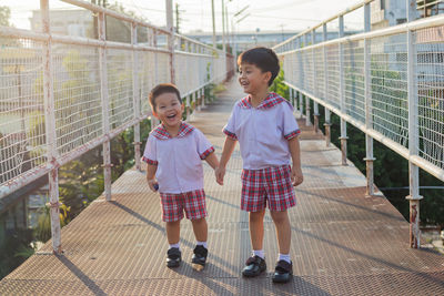 Cute siblings holding hands while standing on footbridge