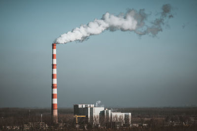 Smoke emitting from factory against sky