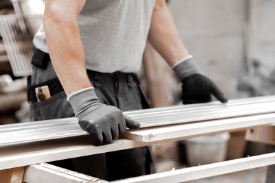 A young builder presses a board with a metal ruler.