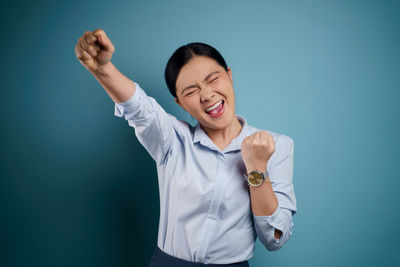 Smiling young woman standing against blue background