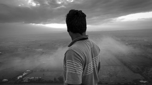 Rear view of man standing on mountain against sky