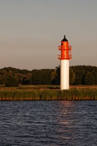 Lighthouse by sea against sky