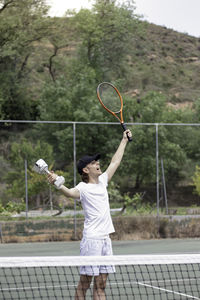 Vertical view of young tennis athlete enjoying his victory with happy and excited face expresion. 