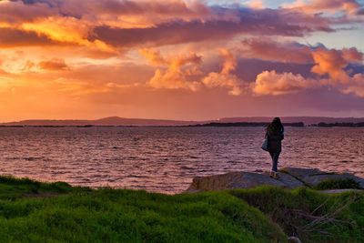 Man standing on beach against sky during sunset