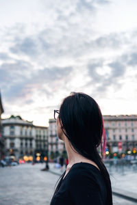 Rear view of woman against sky in city