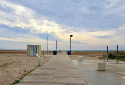 Empty footpath by pier against sky