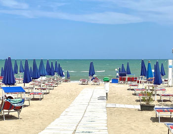 Chairs on beach against blue sky