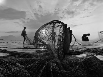 People fishing at beach during sunset