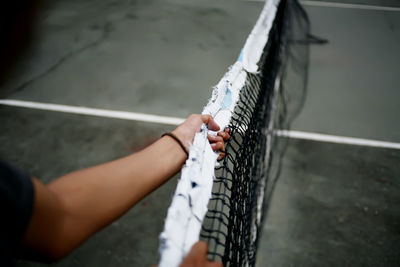 Cropped hand holding tennis net at sports court