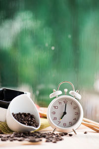 Close-up of alarm clock with roasted coffee beans on table