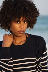 Young black woman standing by the sea wearing striped jumper