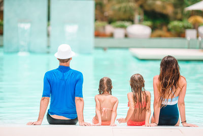 Rear view of people sitting on swimming pool