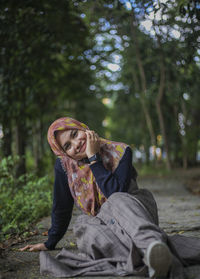 Portrait of smiling young woman sitting at park