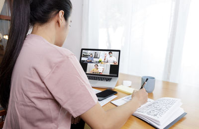 Side view of woman using laptop at home