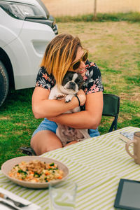 Happy woman hugging dog sitting outdoors