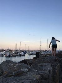Man standing on rock at shore against clear sky
