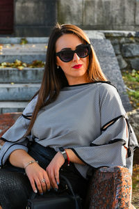 Young woman wearing sunglasses sitting outdoors