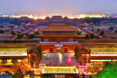 Illuminated buildings in city at sunset