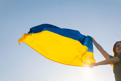 Woman holding a yellow and blue flag of ukraine in outdoors