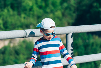 Boy wearing sunglasses while standing by railing
