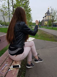 Full length of woman sitting on bench at park