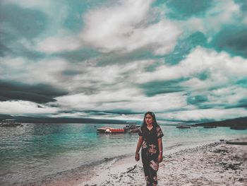 Woman standing at beach against sky