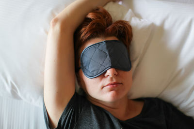 Woman wearing sleep mask on bed at home