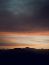 Scenic view of silhouette mountains against dramatic sky