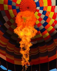 Low angle view of flame under multi colored hot air balloon 
