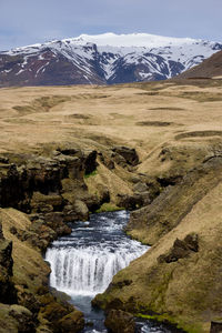 Scenic view of waterfall on snowcapped mountains