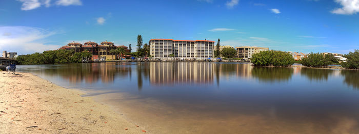 Buildings by lake against blue sky