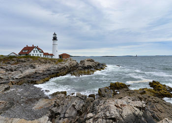 Lighthouse by sea against sky