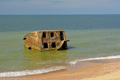 Abandoned built structure on sea shore against sky