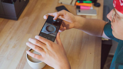 Teenager boy photographing coffee cup through smart phone