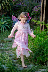 Full length of girl in fairy costume running on footpath at park
