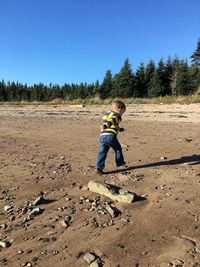 Boy on dirt road against sky